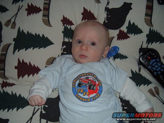 Baby wearing a light blue t-shirt with a circular graphic depicting a red Ford Bronco and the text "Project Bronco Club 78-79"