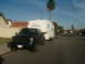 2005 Ford F-250 - A dark blue 2005 Ford F-250 truck is seen towing a white travel trailer down a suburban street.