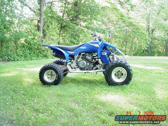 Blue Yamaha YFZ450 ATV parked on grass, side view. Visible 'YFZ' and Yamaha logo