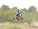2004 Yamaha YFZ450 - A rider on a blue quad bike catches air during a race, with spectators watching from the side.