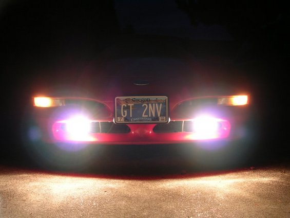 Front of a red car at night, headlights and fog lights on. Oregon license plate reads GT 2NV