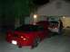 1997 Ford Probe - Two cars are in a garage and driveway at night, one red and one white, with hoods open.
