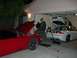 1997 Ford Probe - Two cars are parked in a garage with their hoods or trunks open, suggesting maintenance or repair work is underway.