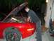1997 Ford Probe - Mechanic works on the engine of a red car with its hood open.