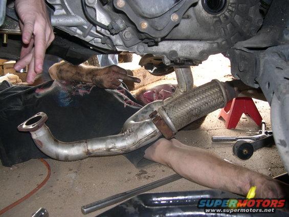 Mechanic working on exhaust pipe under car