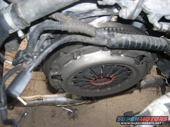 Clutch assembly with orange accents, part of engine bay