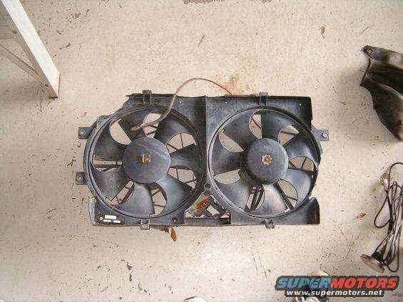 Dual black radiator fans mounted on a black plastic shroud with red wiring