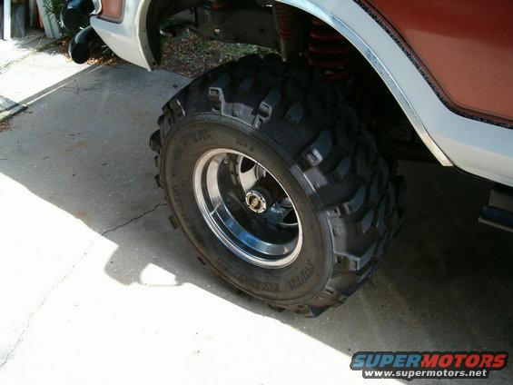 1991 Ford Bronco with large off-road tires and chrome rims, viewed from the side