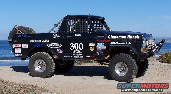 1979 Ford Bronco modified for off-road racing, with roll cage and large tires, parked on a beach