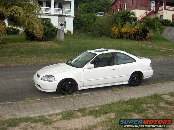 White coupe parked on the side of a road, with a sunroof and black steel wheels