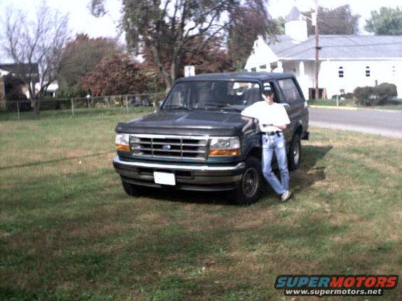 Dark green 1996 Ford Bronco with a person leaning on the front fender