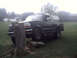 1996 Ford Bronco - A dark SUV is parked on a grassy area with a tree stump in front of it.