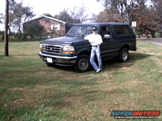 1996 Ford Bronco parked on grass with a person leaning on the driver's side door