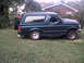 1996 Ford Bronco - A dark green Ford Bronco is parked on a grassy lawn with a house in the background.