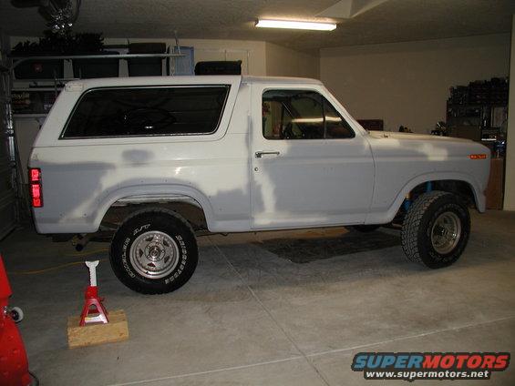 Ford Bronco in garage, primer coat on body, jack under rear wheel