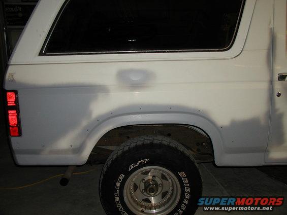 White SUV rear quarter panel with visible bodywork repairs and a Bridgestone tire