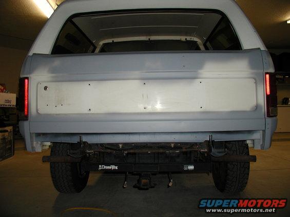 Rear view of a 1986 Ford Bronco with primer on the tailgate and a trailer hitch