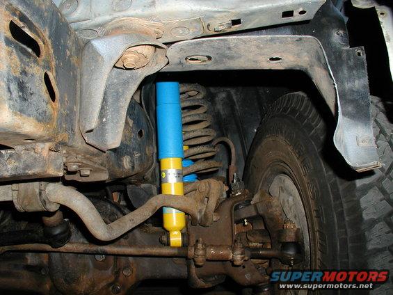1986 Ford Bronco undercarriage showing a new yellow and blue Bilstein shock absorber and suspension components