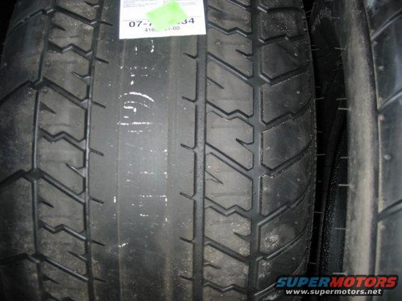 Close-up of two vehicle tires, one with a white sticker showing some numbers