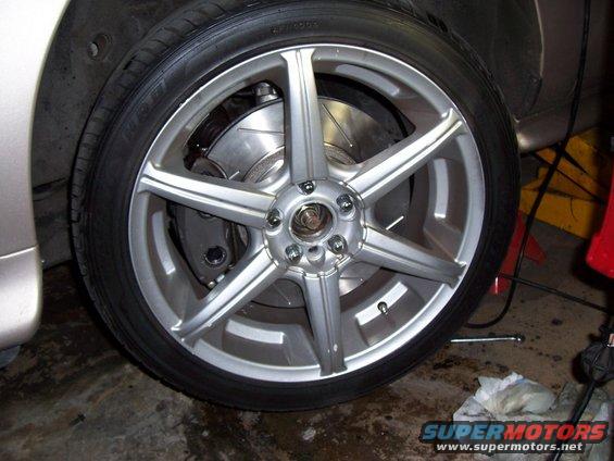 Close-up of a silver 5-spoke aftermarket wheel with a large brake rotor and caliper visible behind it