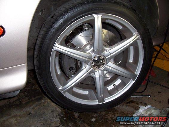 Close-up of a silver 5-spoke alloy wheel with a performance brake caliper and rotor visible