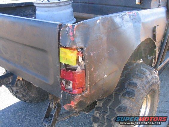 Damaged taillight on dark pickup truck with off-road tires