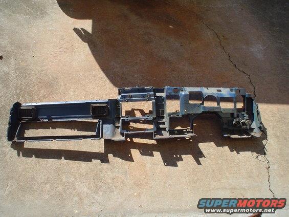 Dashboard frame with air vents and gauge openings, lying on concrete