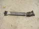 1989 Ford Bronco - A driveshaft component lies on a concrete surface, showing its universal joints and metal construction.
