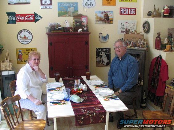 Two people sit at a table set for a meal, surrounded by vintage signs and decor