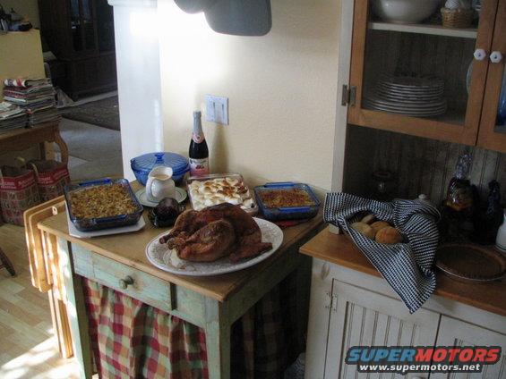 Thanksgiving dinner spread with turkey, casseroles, and bread rolls