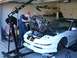 1996 Ford Probe - A mechanic uses an engine hoist to remove the engine from a white 1996 Ford Probe in a garage.
