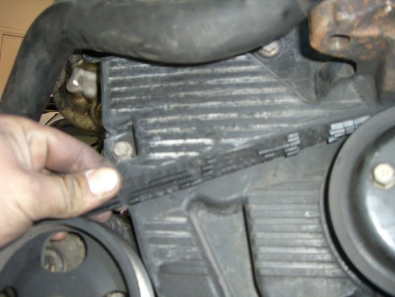Hand checking timing belt tension on engine component