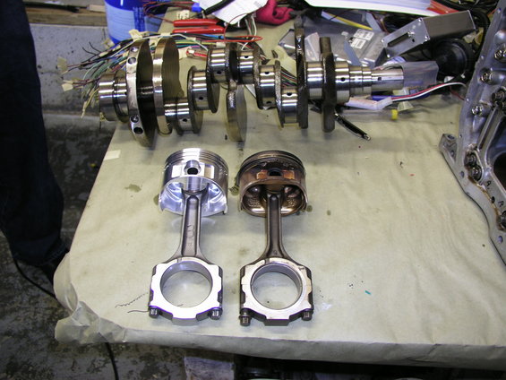 Engine crankshaft and two pistons, one new and one used