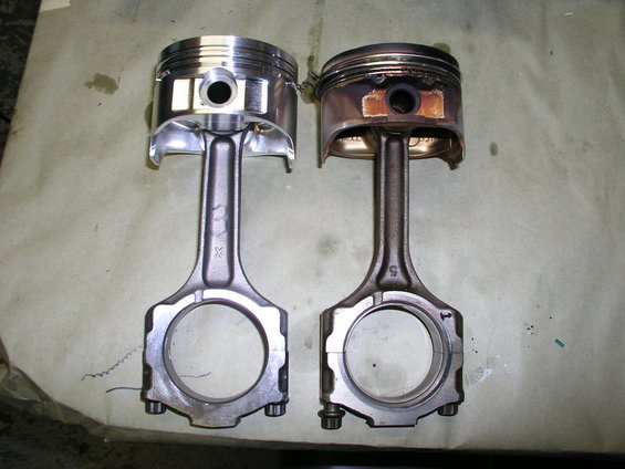 New piston and connecting rod next to a used, carbon-stained piston and connecting rod