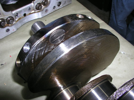 Crankshaft with visible scoring and wear marks, next to engine block components