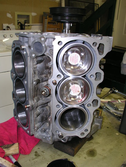 Engine block with pistons visible, on a workbench with tools and a red cloth
