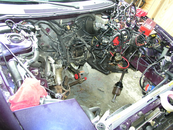 Purple car engine bay with engine removed, drive axles and red rag visible