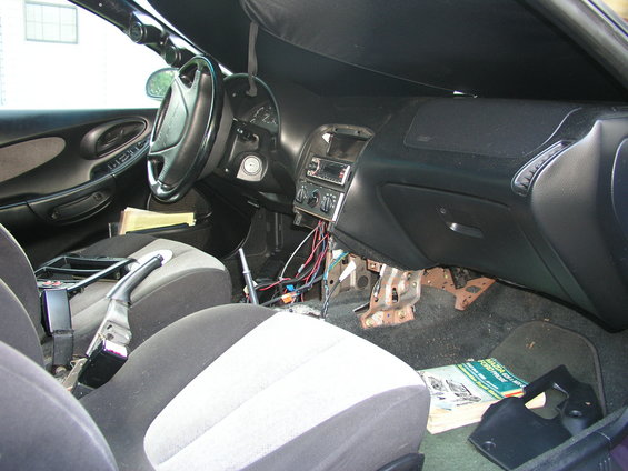 Car interior with dashboard disassembled, showing wiring and exposed metal