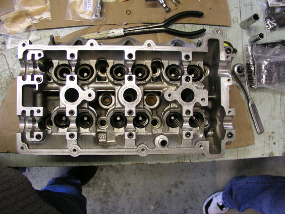 Engine cylinder head with valves and springs, on a workbench with tools