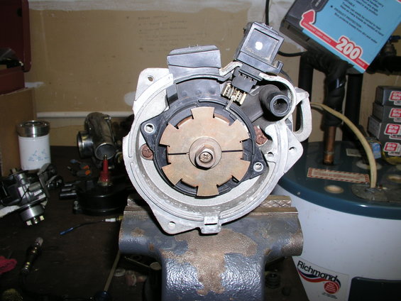 Distributor held in a vise, with electrical connectors and rotor visible