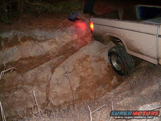 Tan 1980 Ford F-250 truck with rear wheel stuck in dirt ditch