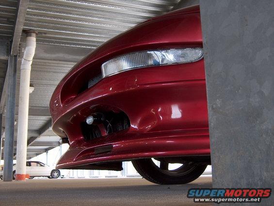 red sports car front end, parked under a structure. another car is visible in the background