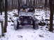 1989 Ford F-350 - An off-road vehicle navigates a snowy, wooded terrain with another vehicle visible in the background.