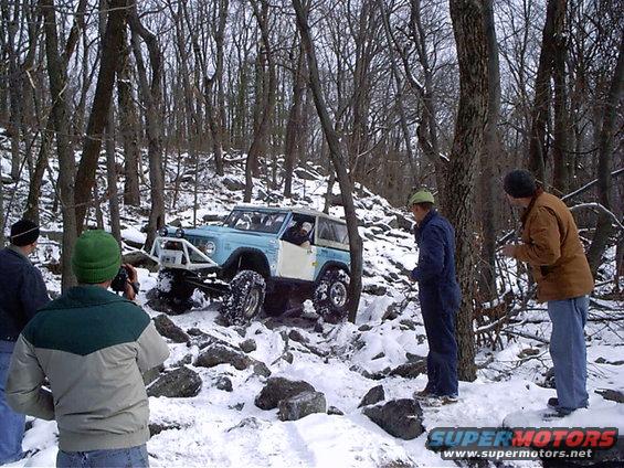 Light blue off-road vehicle with roll cage navigating snowy terrain