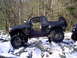 1989 Ford F-350 - A black pickup truck navigates a rocky, snow-covered terrain with its doors ajar.