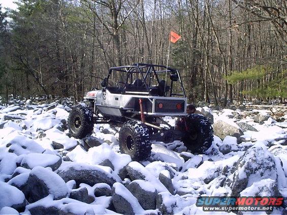 Off-road buggy with roll cage and large tires on snowy rocks