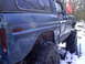 1989 Ford F-350 - This heavily damaged blue SUV is equipped with large off-road tires and is seen in a snowy environment.