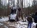 1989 Ford F-350 - An off-road vehicle is overturned in a snowy wooded area with several people observing.