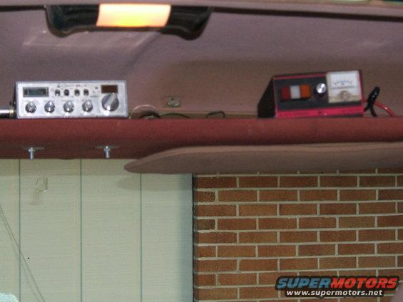 CB radio and battery charger mounted on a red shelf inside a vehicle