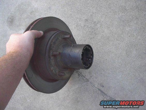 Hand holding brake rotor and hub assembly against concrete wall